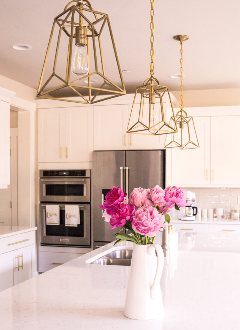 White and gold kitchen, gold lantern pendant lights, pink peonies