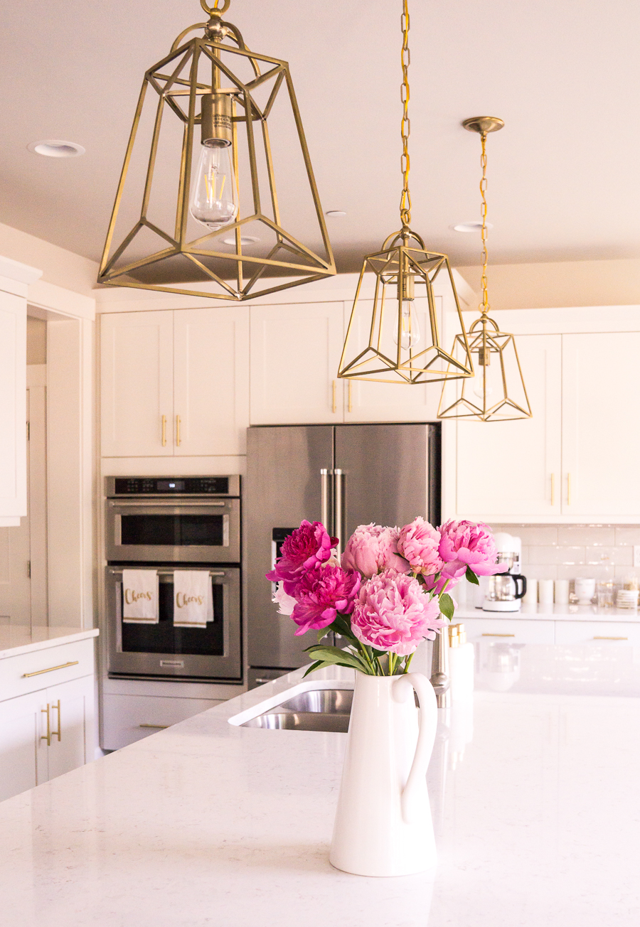 White and gold kitchen, gold lantern pendant lights, pink peonies