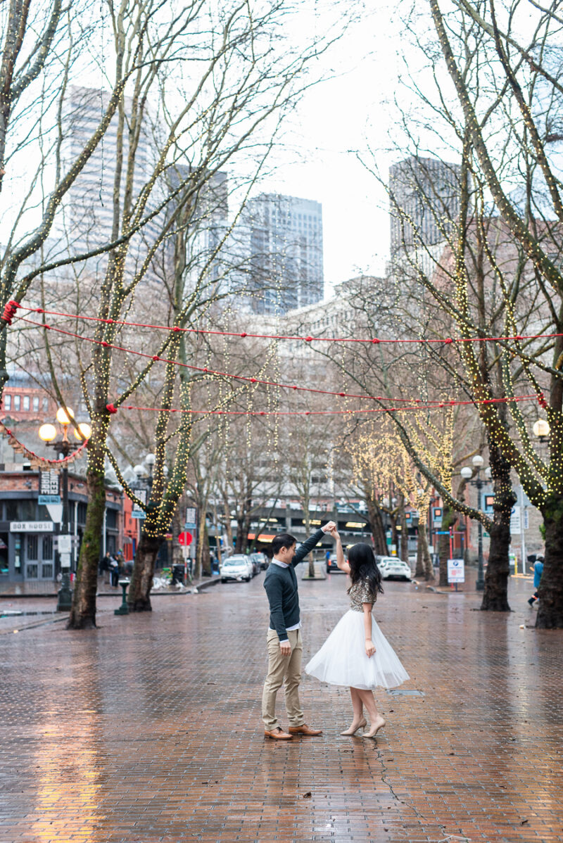 Seattle engagement photos in Pioneer Square, Occidental Park, holiday shoot, rainy engagement photos with clear umbrella, Seattle fashion blogger Just A Tina Bit, midi tulle skirt, embellished top, sequined top