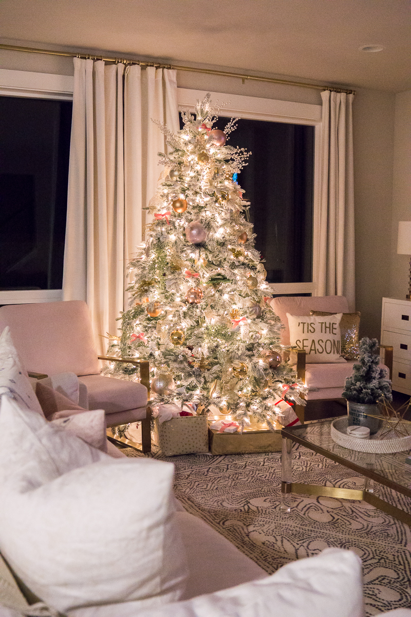 Pink and gold Christmas decorations 2019, blush chairs, living room interior design, flocked Christmas tree, fireplace garland with pink flowers, cozy stone fireplace