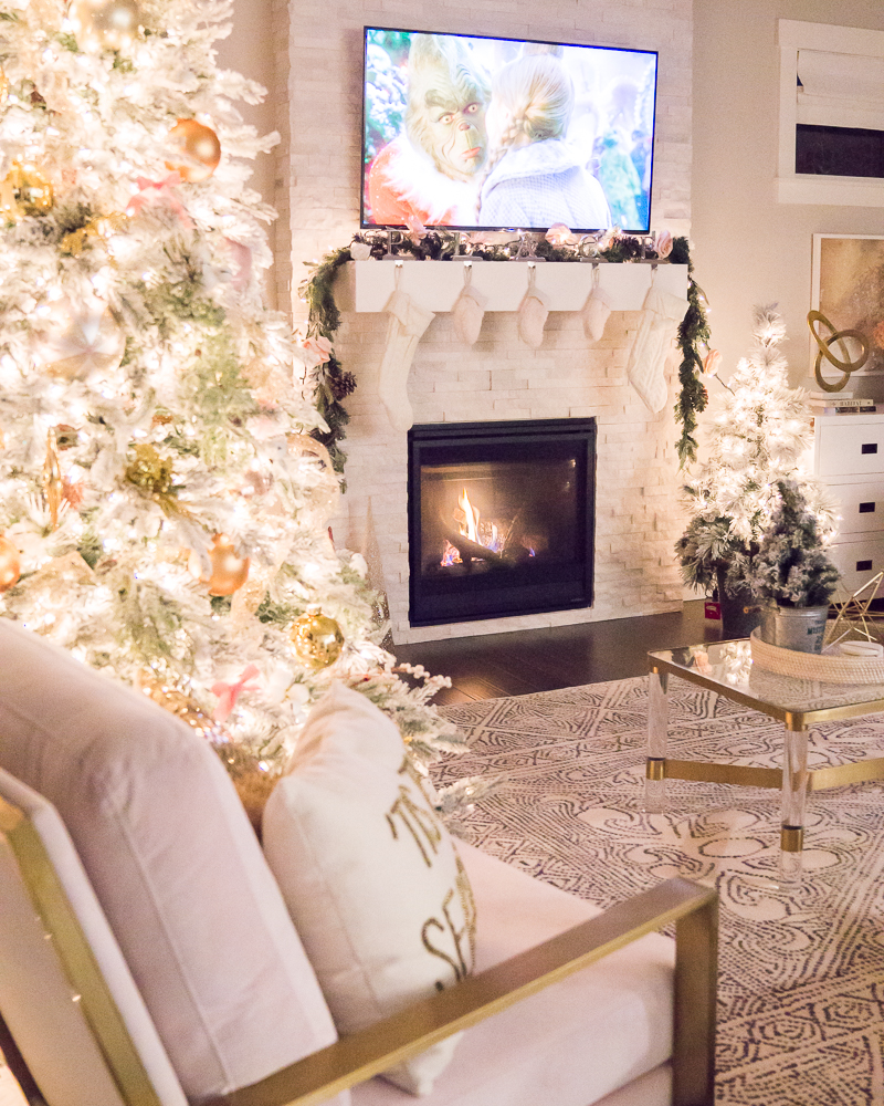 Pink and gold Christmas decorations 2019, blush chairs, living room interior design, flocked Christmas tree, fireplace garland with pink flowers, cozy stone fireplace