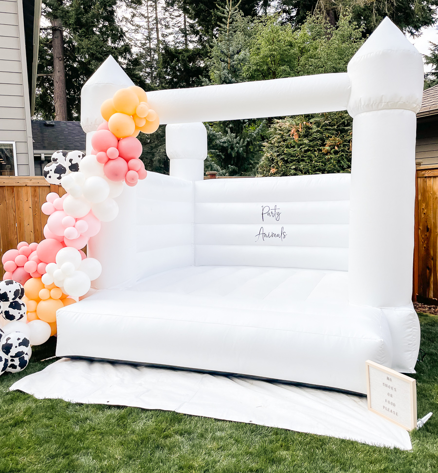 Seattle white bounce house with balloon garland, party animals sign, cow balloons