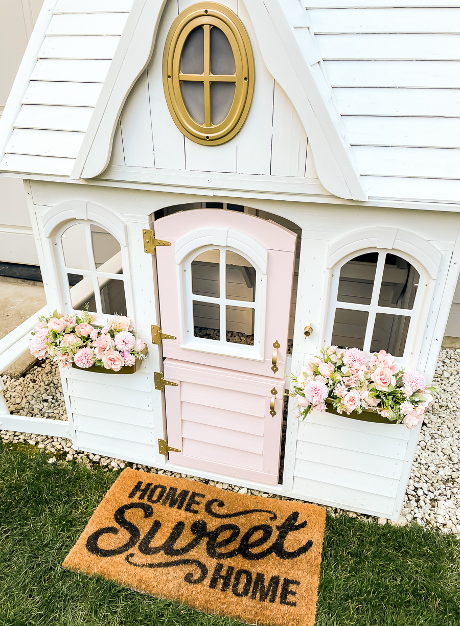 playhouse makeover final result, white blush and gold playhouse with faux flowers and home sweet home doormat