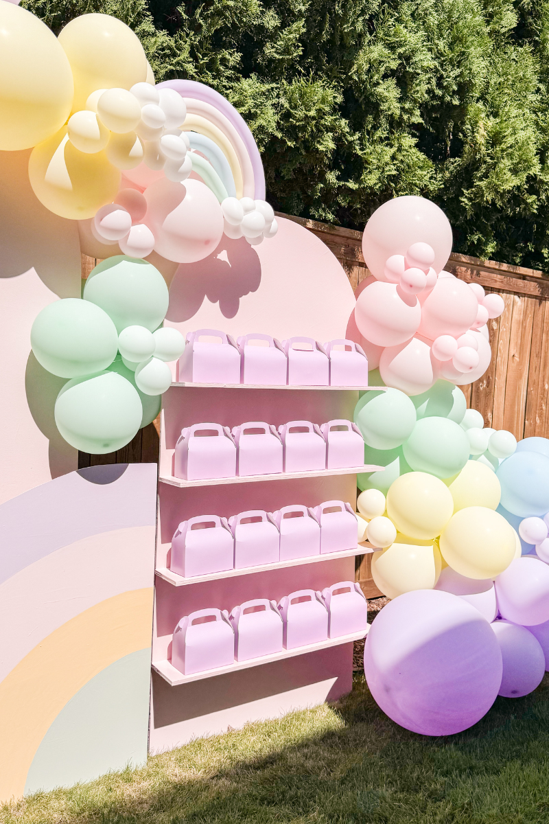 Unicorn theme party favors boxes on a party favor wall with shelves
