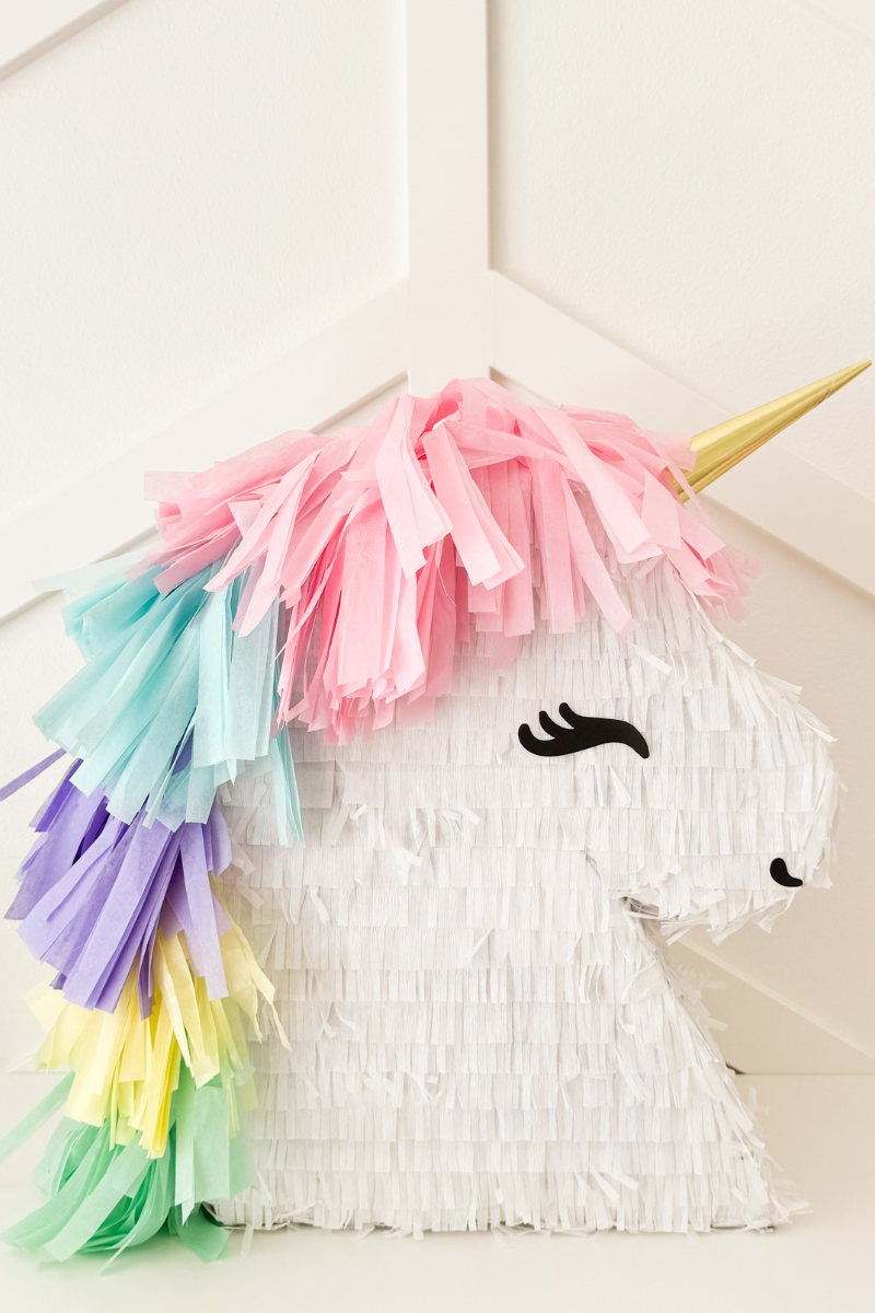 DIY Unicorn Piñata with rainbow mane and gold horn. Made with cardboard and crepe paper